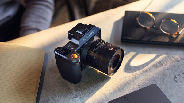 Medium format camera with attached lens on wooden table in natural sunlight.