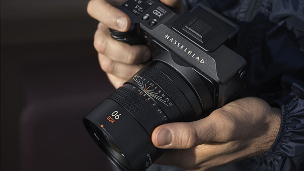 Photographer holding a Hasselblad camera with a Zeiss lens attached.