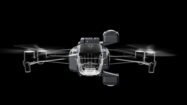 Illustration of a quadcopter drone shown from above with four rotors, rendered in grayscale with transparent shell design against black background.