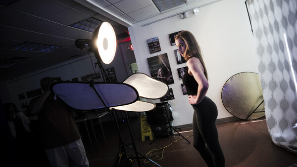 Photographer working with electronic drum pads and studio lighting equipment in a controlled indoor studio setup.