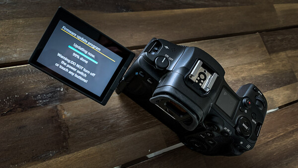 Professional digital camera with articulating LCD screen displaying menu options on wooden surface.