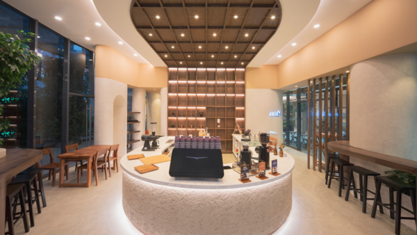 Modern minimalist interior with curved white counter, geometric ceiling, and warm lighting in a commercial space.