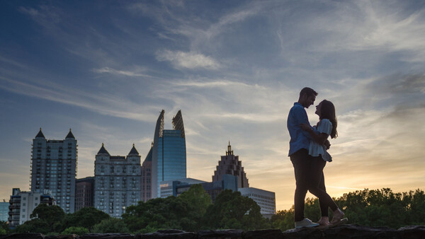 Silhouetted couple embracing against a city skyline at golden hour.