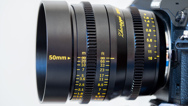 Close-up of a 50mm cinema lens showing focus and aperture scale markings in meters and feet.