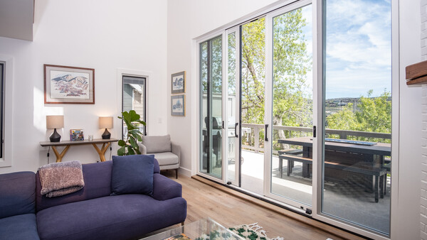 Modern living room with navy sofa, large sliding glass doors opening to a balcony with landscape views.