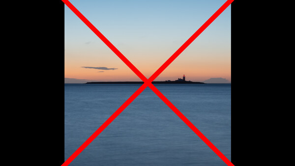 Coastal seascape at dusk with silhouetted lighthouse on distant shore.