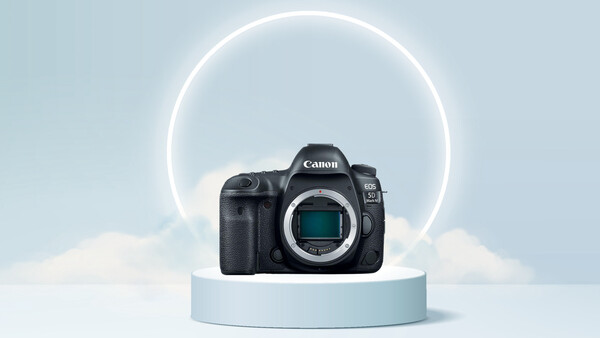Canon EOS R5 mirrorless camera body displayed on a light blue cylindrical pedestal against a minimalist backdrop with a glowing circular neon ring.
