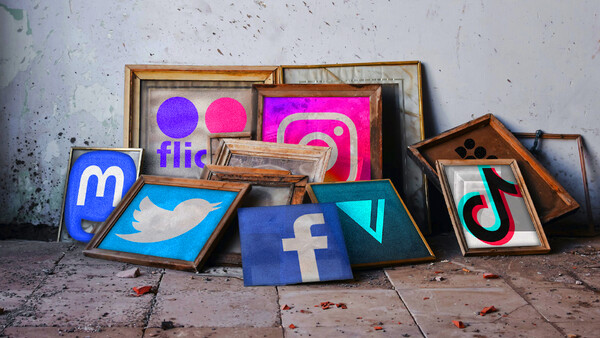 Social media platform logos displayed in wooden frames leaning against a weathered concrete wall.