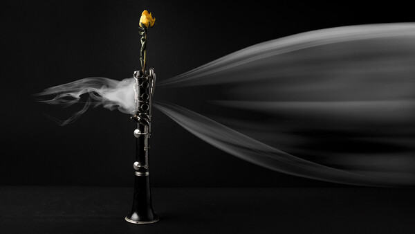 Brass trumpet with smoke billowing from the bell against a black background.