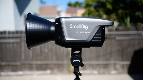 SmallRig RC 450B LED light mounted on a light stand in outdoor daylight with buildings visible in the background.