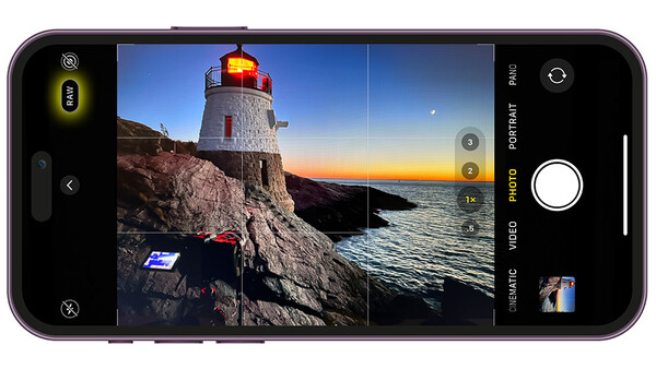 Screenshot of smartphone camera app displaying a lighthouse at sunset with grid overlay and video mode controls visible.