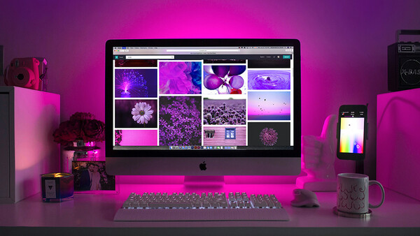 Mac monitor displaying a grid of magenta and purple-toned landscape and floral photographs in a color-graded workspace.