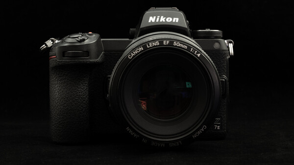 Nikon Z mirrorless camera with Canon 50mm f/1.4 lens mounted against black background.