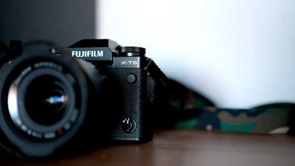 Fujifilm X-T5 mirrorless camera with attached lens on wooden surface.