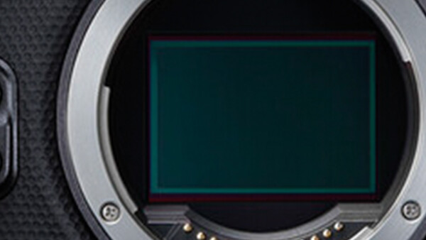 Camera sensor with green-tinted display showing dust or debris particles on the imaging surface.