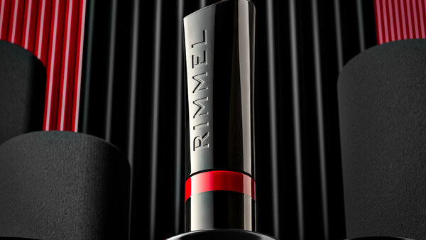 Luxury cosmetic product shot featuring a silver and red lipstick against striped backdrop with spherical elements.