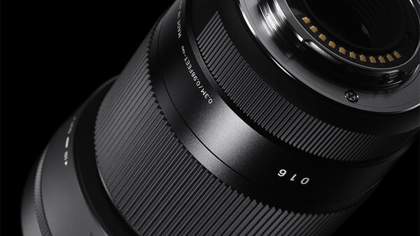 Close-up of a telephoto lens barrel and focus ring against a black background.