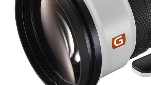 Close-up view of a wide-angle camera lens with glass elements visible and an orange G-series logo on the white barrel.