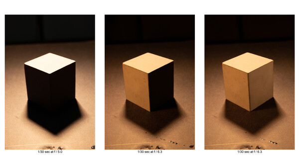 Three white cubes under different lighting conditions showing aperture and exposure variations.