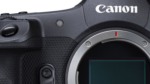 Close-up of Canon mirrorless camera body showing grip, controls, and sensor with red alignment dot.