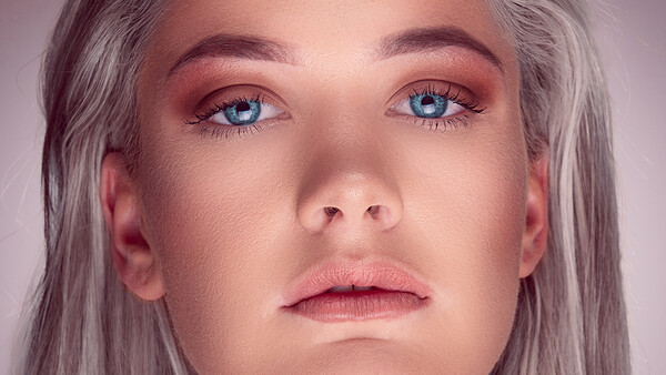 Close-up portrait of a person with gray hair and blue eyes looking slightly downward.