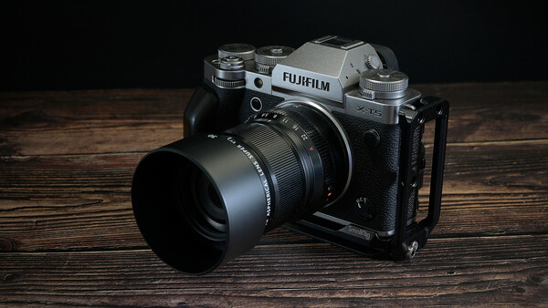 Fujifilm X-T4 mirrorless camera with lens and hood on wooden surface.