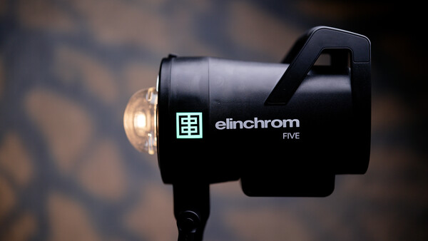 Elinchrom Five monolight with dome diffuser against blurred background.