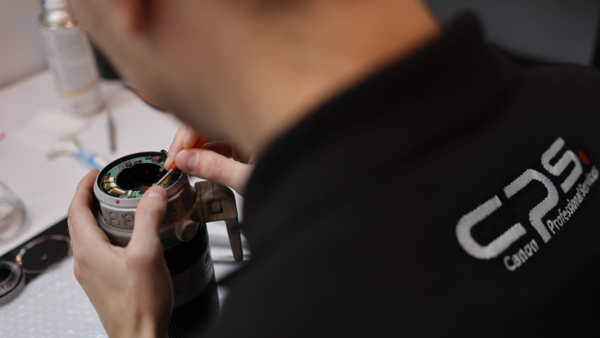 Photographer in black shirt examining a camera lens up close.