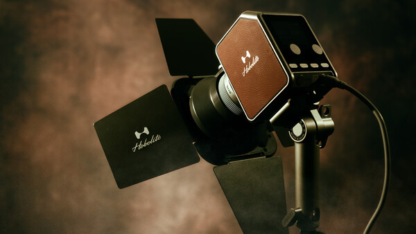 Studio lighting kit with three-light setup mounted on stands against brown textured backdrop.