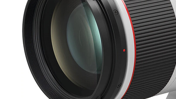 Close-up of a telephoto lens showing glass elements and red accents on the barrel.