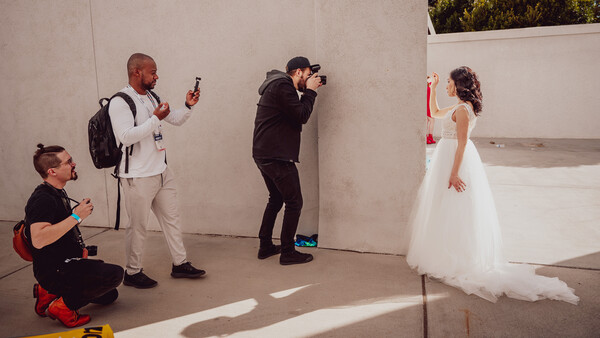Photography team capturing a bride in a white wedding dress during an indoor photo shoot.