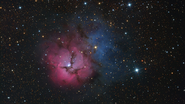 Deep space nebula with pink emission clouds and blue reflection nebula surrounded by stars.