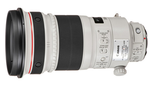 Canon telephoto lens with white barrel and focus ring against white background.