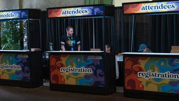 Three registration booths with colorful geometric designs and attendee staffing at what appears to be an event or conference venue.