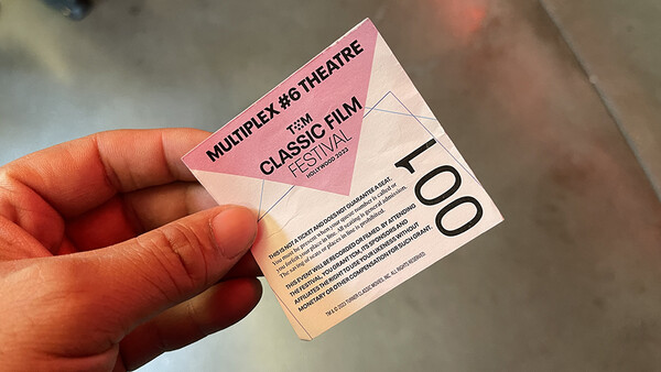 Hand holding a pink multiplex theater ticket stub for a classic film festival.