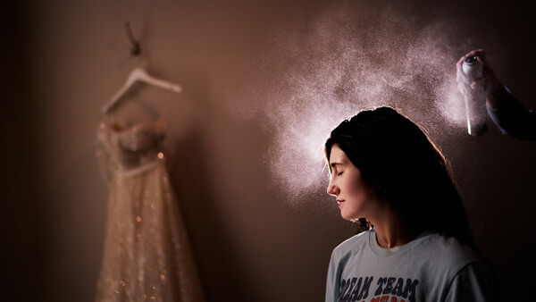Young woman in profile gazes downward while suspended figures and dramatic light rays create a surreal, dreamlike atmosphere.