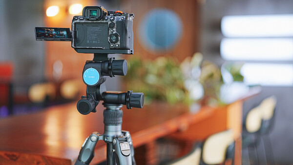 Professional camera mounted on tripod with articulating arm and ring light in studio setting.