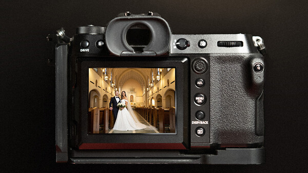 Mirrorless camera displaying a wedding ceremony photograph on its rear LCD screen.