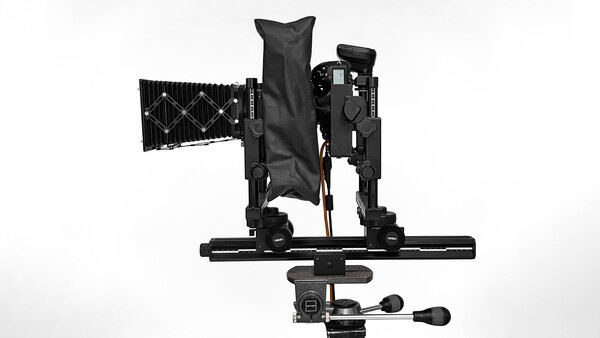 Overhead view of a camera rig with articulating arms, mounting plate, and control handle on white background.