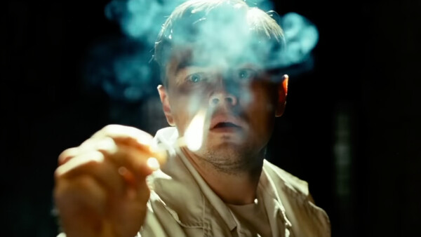 Man with dramatic lighting smoking cigarette against dark background.