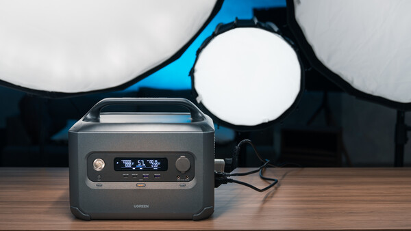 Portable power station with digital display positioned on wooden surface under professional studio lighting.