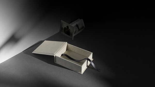 Open book with pages casting sharp shadows under dramatic directional lighting against a dark background.
