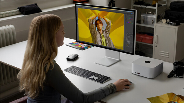 Designer working on portrait photo editing in Adobe Lightroom with vibrant yellow background on monitor.