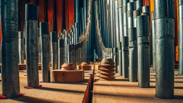 Industrial interior with metal cylindrical pipes creating geometric perspective and warm sandy ground lighting.