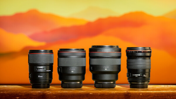 Four camera lenses arranged in a row against a warm sunset sky backdrop.