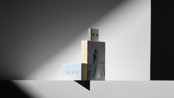 Artistic composition of a USB drive with photo printing mounted on wooden blocks against dramatic shadow lighting.