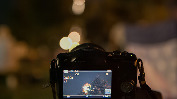 Camera LCD screen displaying a nighttime scene with bokeh lights in the background.
