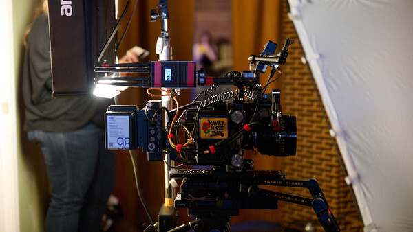 Custom-built camera rig with mounted cinema camera, wireless monitor, and LED lighting on tripod in hallway.