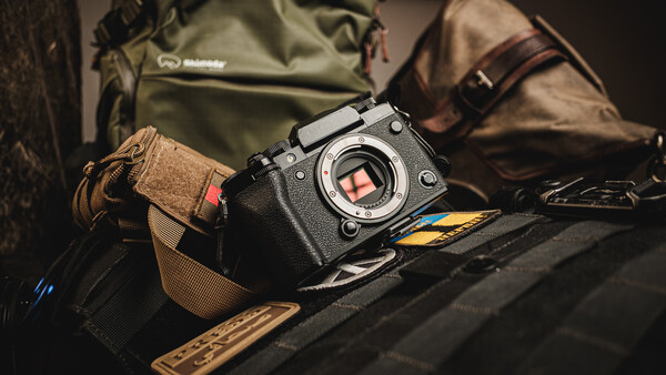 Black mirrorless camera with visible sensor positioned on photography gear and canvas bags.