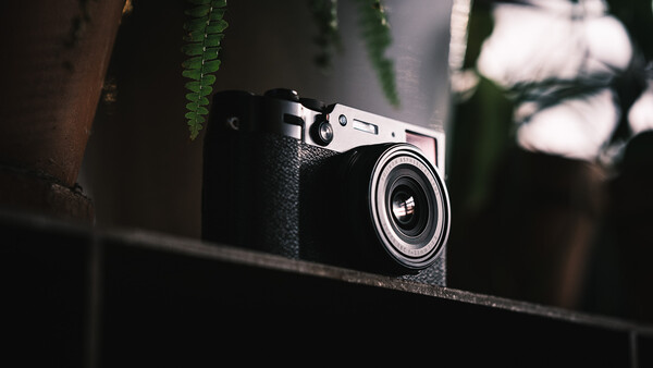 Vintage rangefinder camera with black leather body and chrome top plate resting on a dark surface.
